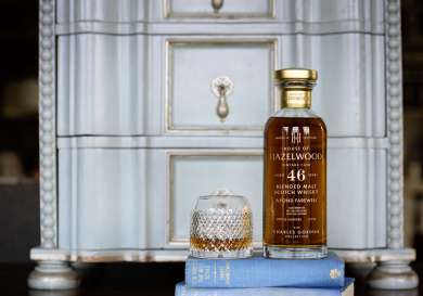 Bottle of whisky and whisky glass on stack of books.