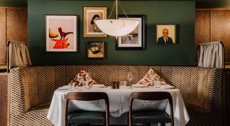 Interiors at carmelinas restaurant with green walls and curved banquette seating.