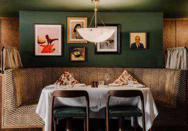 Interiors at carmelinas restaurant with green walls and curved banquette seating.