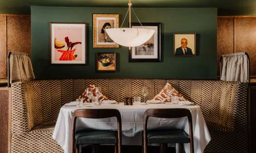 Interiors at carmelinas restaurant with green walls and curved banquette seating.