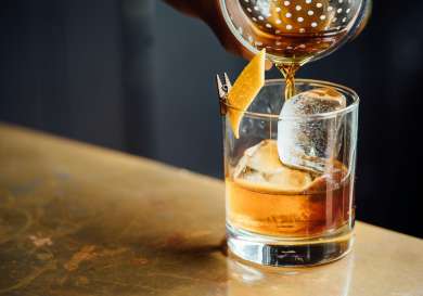  a cocktail being made with a slither of orange peel.