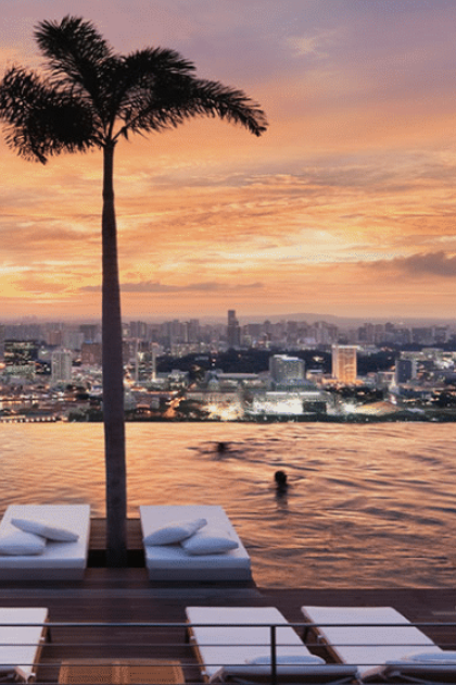 Infinity pool at sunset with palm trees in Singapore.