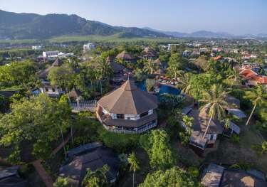 Circular buildings with thatched roofs sit among lush tropical greenery.