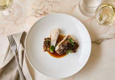 Fish dish served on marble table with a glass of wine.