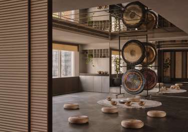 Wellness hotel room with singing bowls arranged on the floor with pouffes.