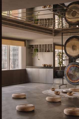 Wellness hotel room with singing bowls arranged on the floor with pouffes.