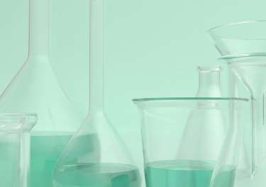 Scientific beakers on mint-green background.