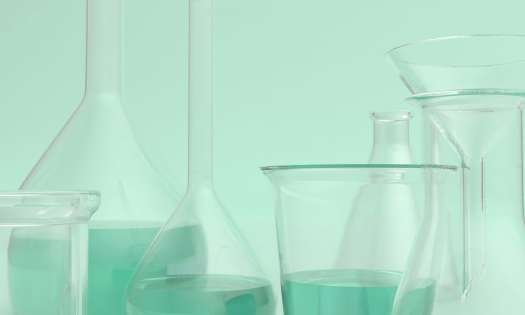 Scientific beakers on mint-green background.