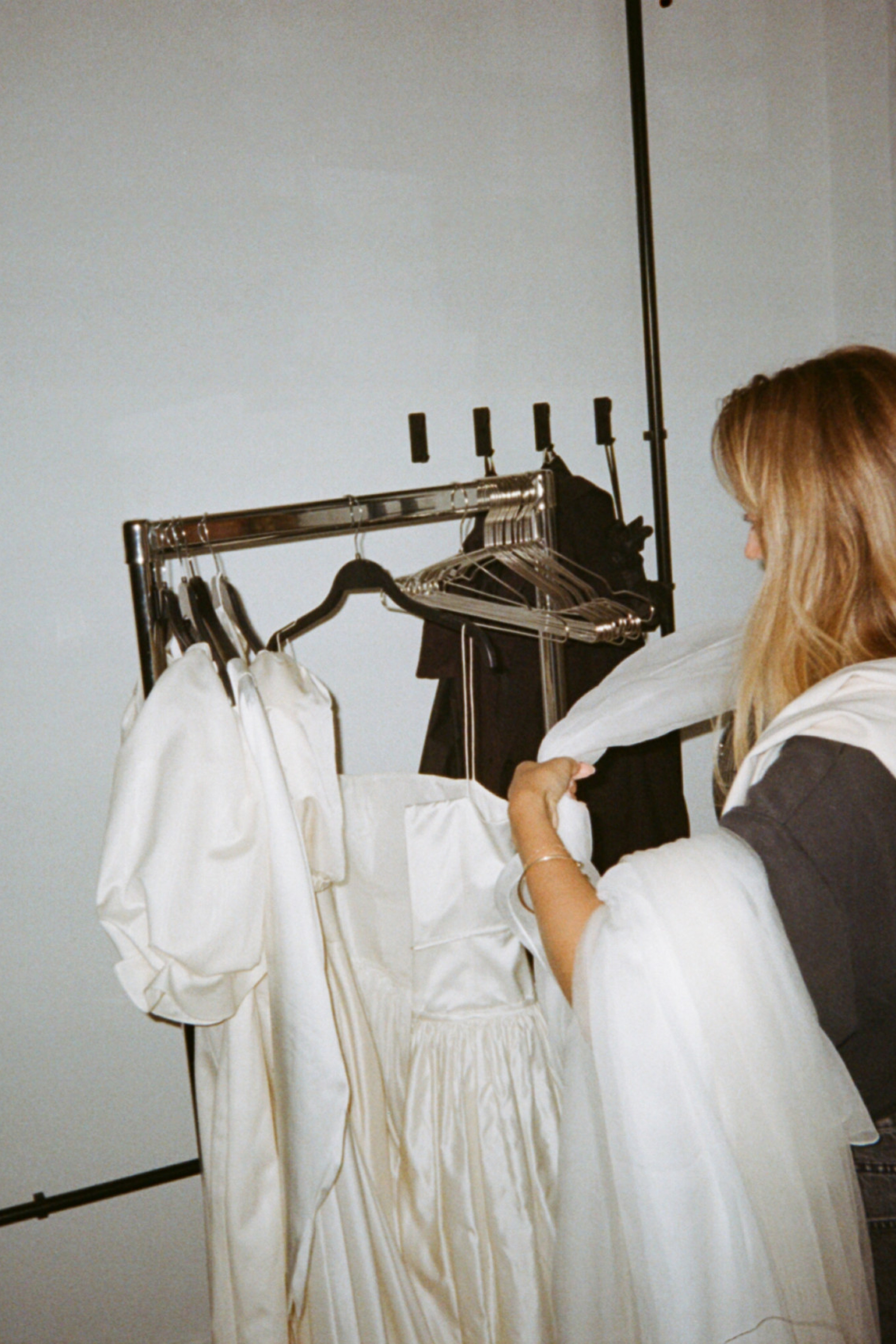 ally voss placing bridal garments on a clothes rail