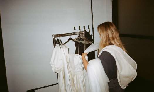 Ally voss placing bridal garments on a clothes rail.