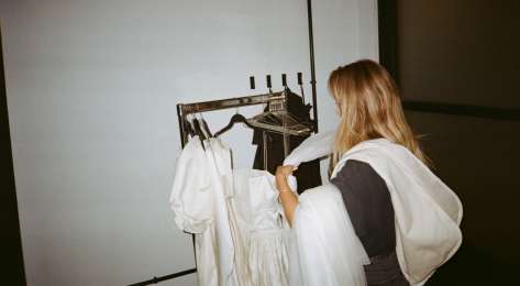 Ally voss placing bridal garments on a clothes rail.