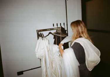 Ally voss placing bridal garments on a clothes rail.
