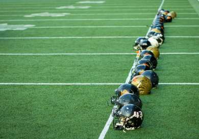 Line of american football helmets on pitch .