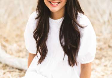 Amy lieu sitting on branch wearing white dress.