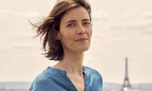 Anne-laure pressat smiling in paris wearing blue blouse.