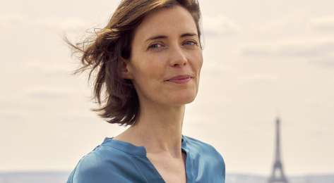 Anne-laure pressat smiling in paris wearing blue blouse.