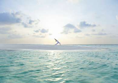 Person doing yoga in maldives by the sea.