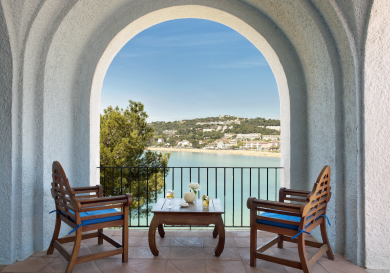 Balcony at hotel with two chairs and a table.