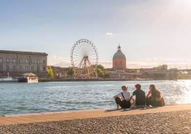 Three people sat beside a river in toulouse.