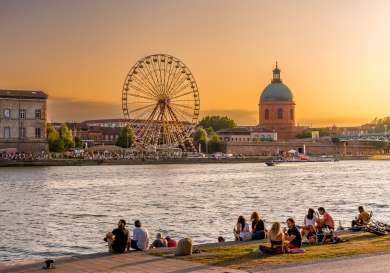 People sitting on the riverbank in Toulouse.