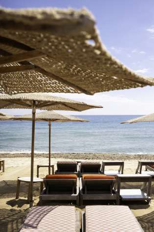 Four beach sunbeds and an array of parasols.