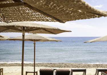 Four beach sunbeds and an array of parasols.