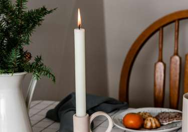 Single candle on kitchen table with orange slices .
