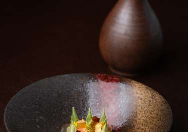 Crab salad dish on wooden table with small ceramic vase in the background.