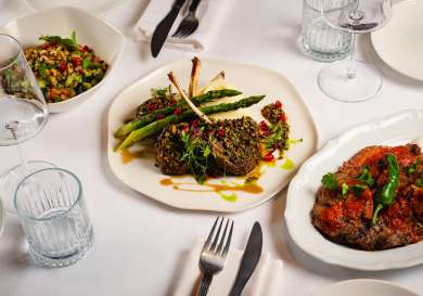 Three dishes arranged on restaurant table with white tablecloth.