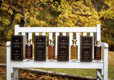 Four bottles of whisky lined up on white bench.