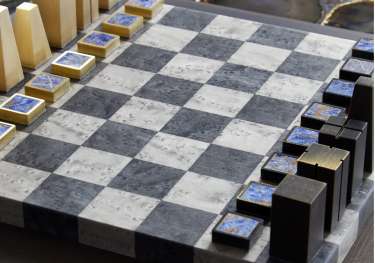 A modern chess set with rectangular pieces stands on a marble-patterned board.