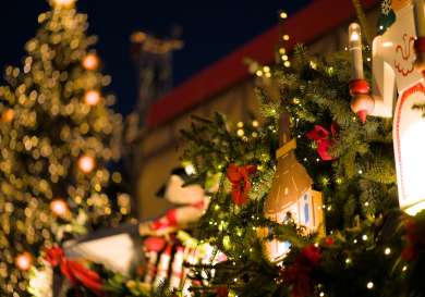 Close-up of fairy lights at christmas market with a tree in the background.