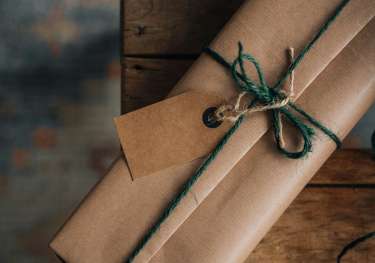 Christmas present wrapped in brown paper and with green string.