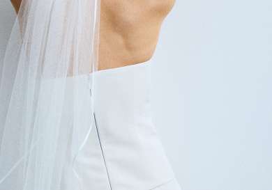 Model posing in wedding dress and veil.