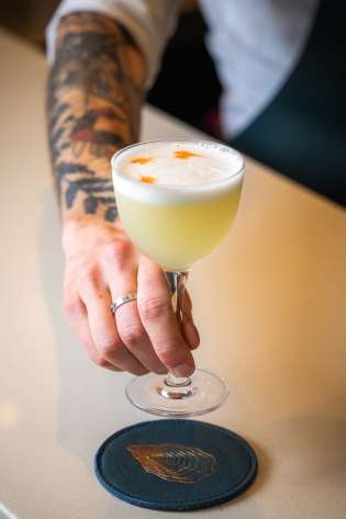 Barman holding cocktail at restaurant.