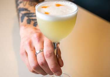 Barman holding cocktail at restaurant.