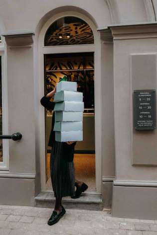 Person carrying blue boxes containing pastries.