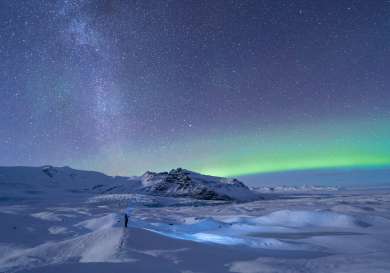 Northern lights against snowy landscape at night.