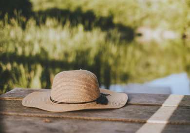 Straw hat laid on wooden jetty.