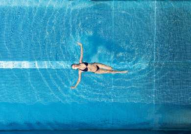 Person floating in a swimming pool .