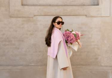 Woman posing with a bouquet of pink flowers.