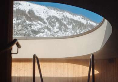 Photo of pool in hotel with snowy hills visible through a window .