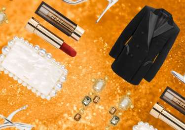 Glam beauty and fashion items on gold glitter background.