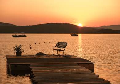 Photo of chair on jetty during sunset .
