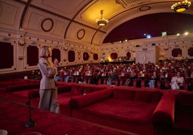 Hermione olivia giving a talk to a theatre of people.