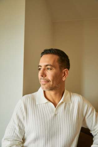 Man posing in cream polo top.