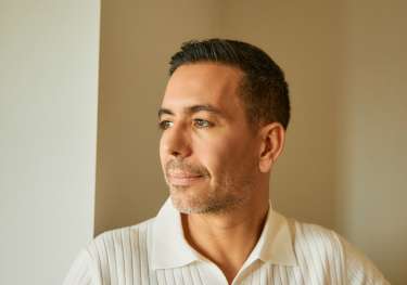 Man posing in cream polo top.