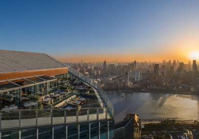 Aerial view of hotel with views of shanghai and sun rising in the background.