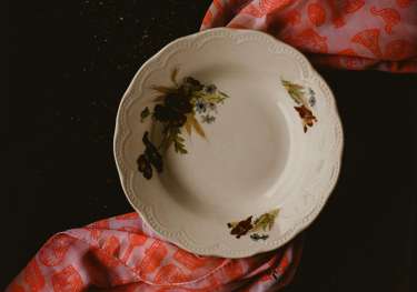 Floral plate with patterned scarf underneath .