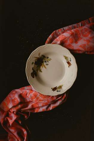 Floral plate with patterned scarf underneath .